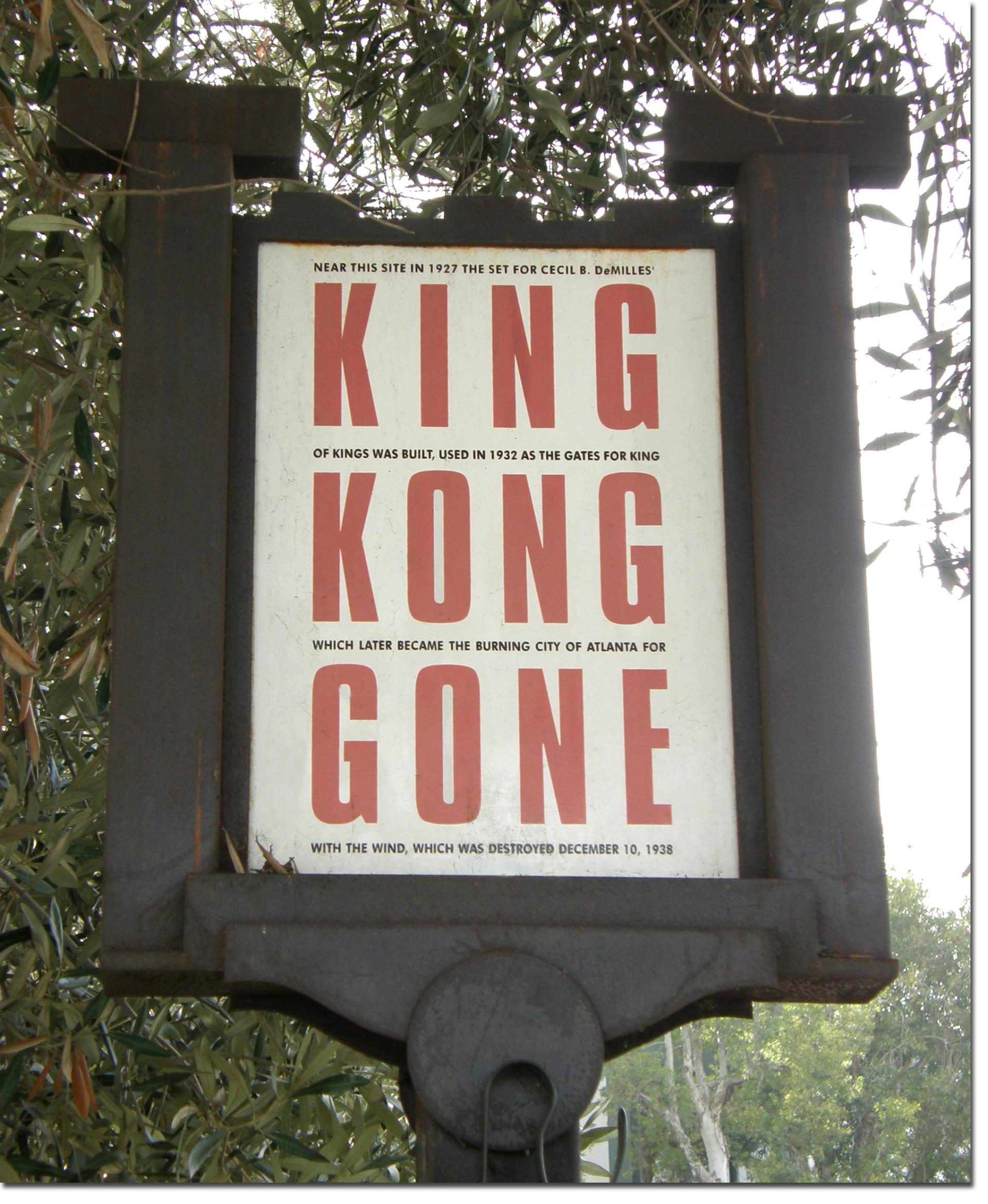 Image of sign encased in black frame that reads Near this site in 1927 the set for Ceci & Demilles King of kings was built, used in 1922 as the gates for king kong which later become the burning city of Atlanta for gone with the wind, which was destroyed December 10, 1928 in alternating red and black text.