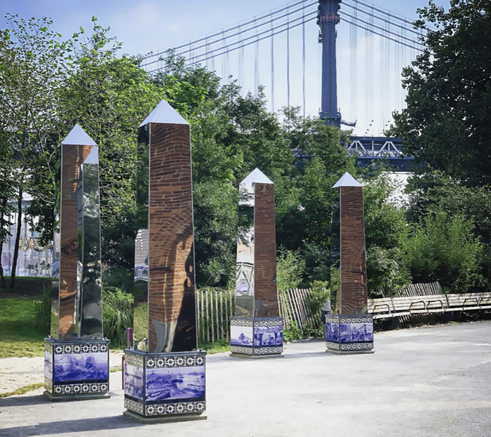 Image of four obelisk reflective pillars with photographic images at the base.